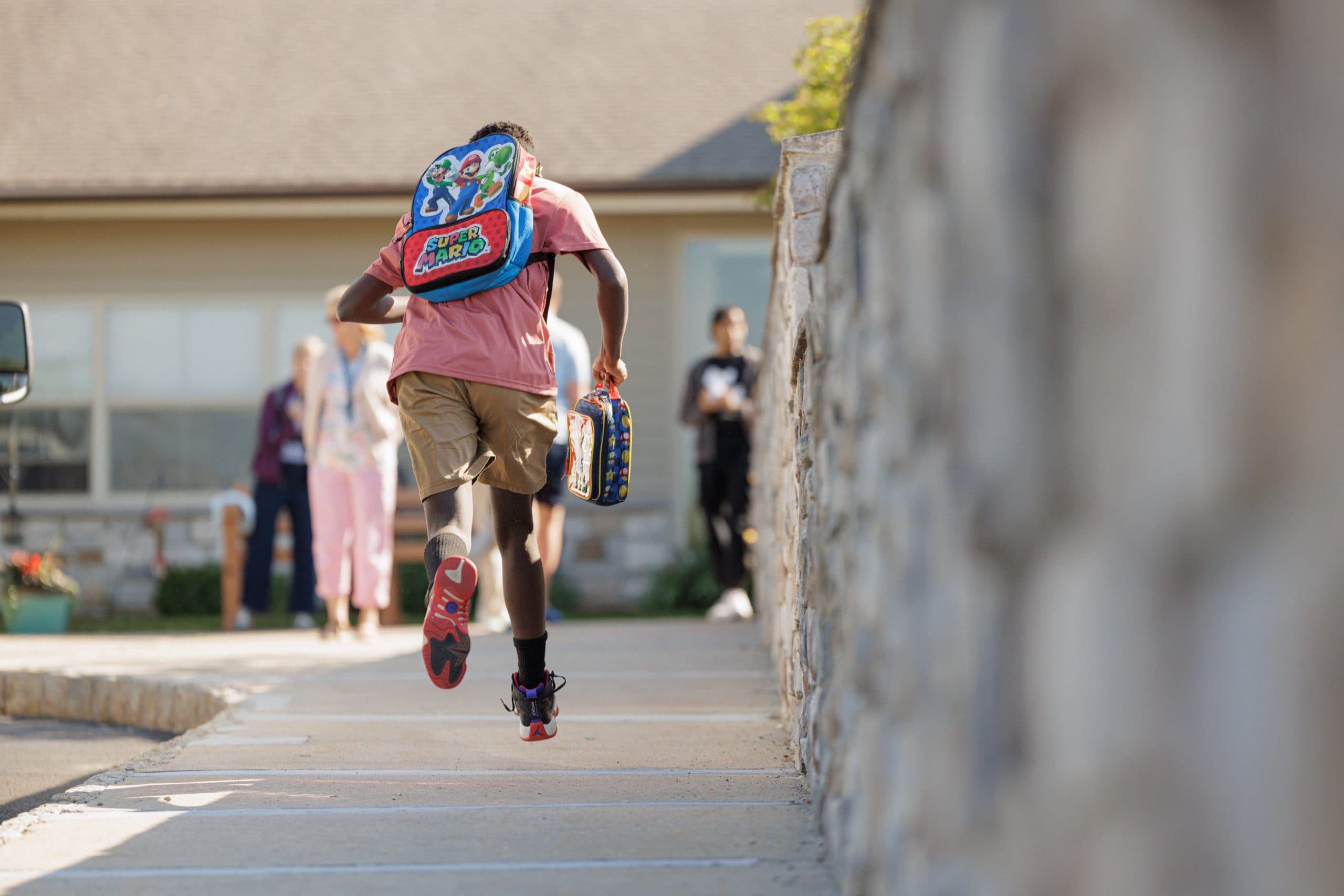 A child running along a path with a backpack